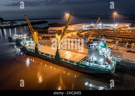 Ship Offloading Cargo at Docks at Night Stock Photo