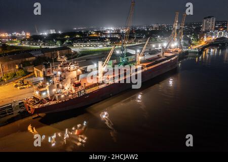 Ship Offloading Cargo at Docks at Night Stock Photo