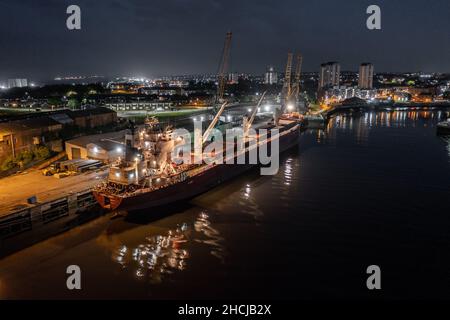 Ship Offloading Cargo at Docks at Night Stock Photo