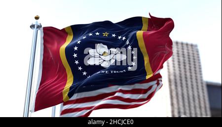 the flag of the US state of Mississippi waving in the wind with the American flag blurred in the background. Mississippi was admitted to the Union on Stock Photo