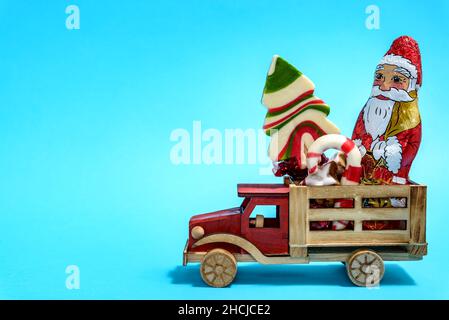Christmas holiday celebration concept. Wooden toy truck with Christmas sweets on blue background. Stock Photo