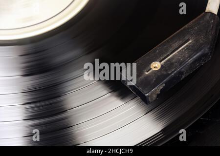 Black vinyl record spinning on the turntable. Analog audio playback. Furrows of music tracks. Long playing and vintage object Stock Photo