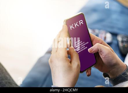 New York, USA, November 2021: Young woman using her mobile phone with the application of the American investment company KKR. Finance and economy. Bus Stock Photo