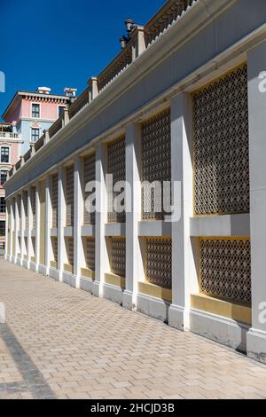 Side view of a decorated long wall fence on a tiled floor against a blue sky in Doha, Qatar Stock Photo