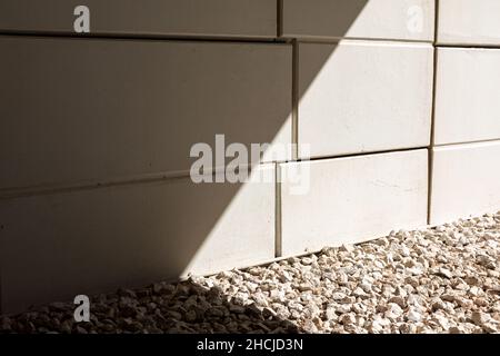 Closeup of a tiled ceramic wall with a sunny stony pebbles floor Stock Photo