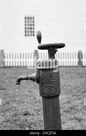 The outdoor water faucet stands against the house in the background. Canterbury Shaker Village, New Hampshire USA. The image was captured with analog