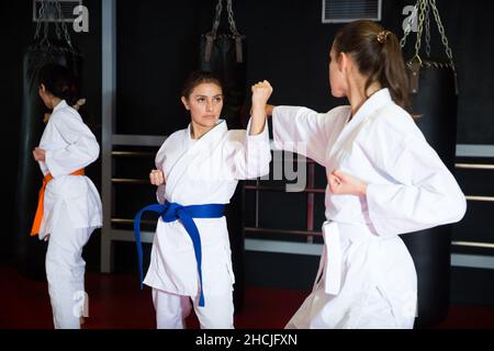 Portrait of woman wearing white kimono sparring with female opponent during martial arts training Stock Photo