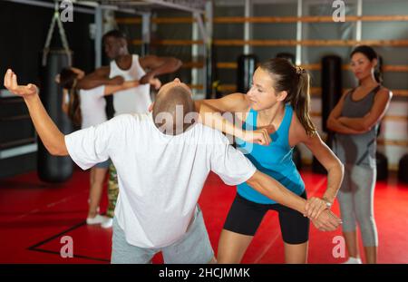 Active girl conducts painful grip on self-defense training in gym Stock Photo