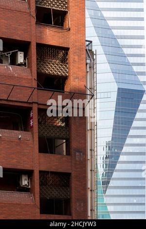 The glass facade of the Sumitomo Fudosan Roppongi Grand Tower behind a brick apartment building in Roppongi, Tokyo, Japan. Stock Photo