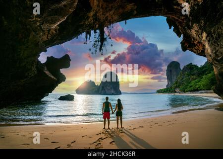 Young couple enjoying beautiful sunset at Railay beach, Krabi in Thailand. Stock Photo