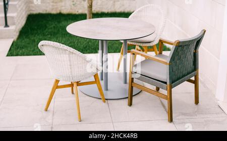Armchairs and chairs near a round table on a tile in the street Stock Photo
