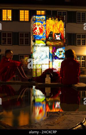 Basel, Switzerland - February 21. Carnival revellers in red costumes at the fountain on the cathedral square Stock Photo