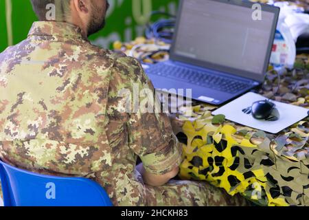 Data Entry Soldier with a laptop in Front of him inside a Military Camp. Stock Photo