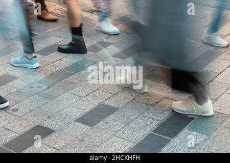 Motion blur of walking people in the street. Low angle view of crowded street background photo. Stock Photo