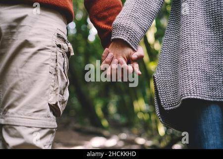 Close up of couple holding hands with green forest nature background. Concept of love and relationship with adults man and woman heterosexual people i Stock Photo