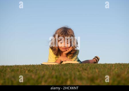 Smart child boy reading book in park outdoor. Clever kids read book in nature background. Stock Photo