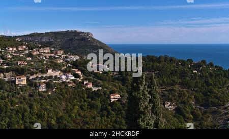 Beautiful view over the wood-covered hills of the mediterranean coast near small village Eze at the French Riviera with residential buildings. Stock Photo