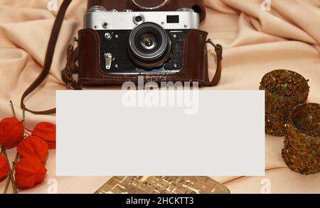 Flatlay. Film camera in case, notebook, fisalis and candlesticks lie on a light beige background. Stock Photo