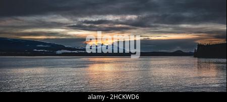 Scenic view of the orange cloudy dramatic sky reflected on the sea at sunset Stock Photo