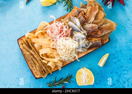 Dried Seafood Mix with Squid, Tuna, codfishon, yellow minke on Plate Top View. Cured Dehydrated Fish Fillet as Beer Snack Stock Photo