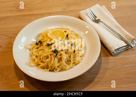 Italian Lemon Pasta or Tagliatelle al Limone on a White Plate with Parsley Stock Photo