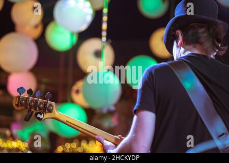 Electric Bass guitar player on stage. Rear view of musician. Stock Photo