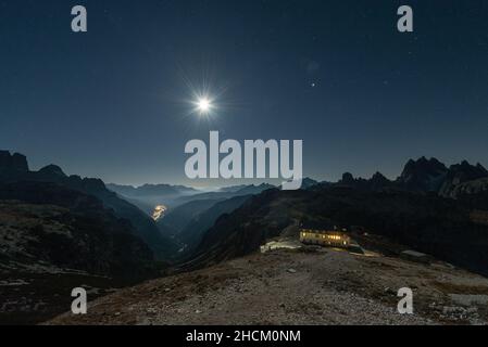 View from the Auronzo Hut below the Tre Cime di Lavaredo south towards mountain ranges and peaks of the Dolomites in the bright moonlight, Italy Stock Photo