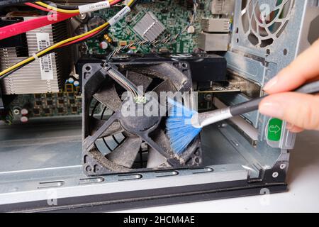 A computer master cleans the dust of the cooler of the ventilation of the system unit Stock Photo