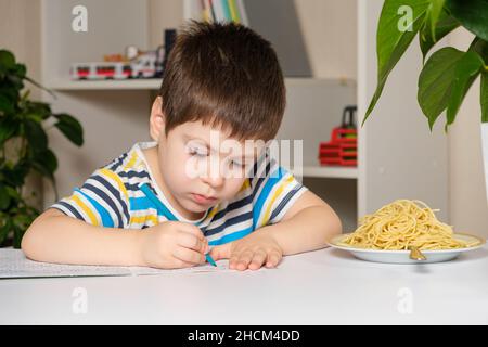 Preschool child learns to write, writes copybook. Stock Photo