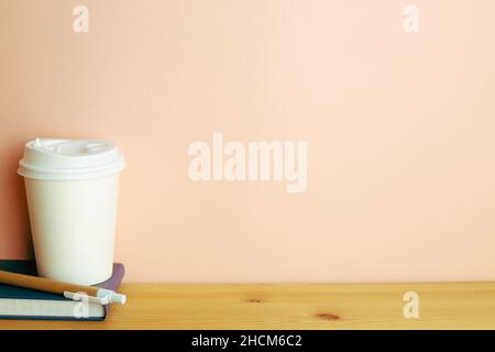 Notebook, pen, paper coffee cup on wooden desk. pink wall background. workspace Stock Photo