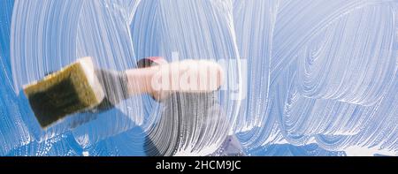 man with rubber glove cleaning window with sponge and soap on a window Stock Photo