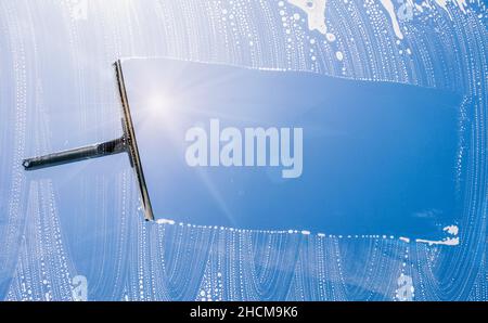 cleaning window with squeegee against blue sky, with copyspace for your individual text. Stock Photo
