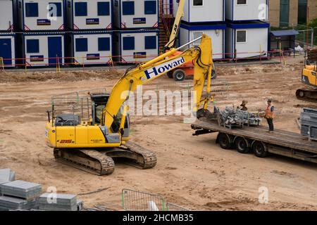 Construction site building materials delivery (excavator unloading steel components from back of truck) - Hudson Quarter, North Yorkshire, England UK. Stock Photo