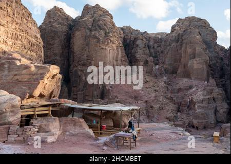 Petra, Jordan. 21st Nov, 2021. A Bedouin woman sells drinks on a rocky plateau in front of the wall of the royal tombs in the ancient Nabataean city of Petra. Credit: Sebastian Kahnert/dpa-Zentralbild/dpa/Alamy Live News Stock Photo