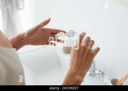 Cropped view of african american woman pouring lotion on cotton pad in bathroom Stock Photo