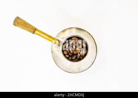 Fresh italian coffee beans in old vintage silver coffee making pot with golden handle isolated in white background. Stock Photo