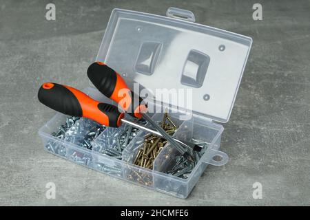 Box with screws and screwdrivers on gray textured background Stock Photo