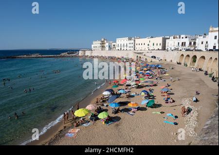 Gallipoli, Puglia, Italy. August 2021. The sandy beach in the old town is packed with people bathing and sunbathing. Stock Photo