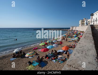 Gallipoli, Puglia, Italy. August 2021. The sandy beach in the old town is packed with people bathing and sunbathing. Stock Photo