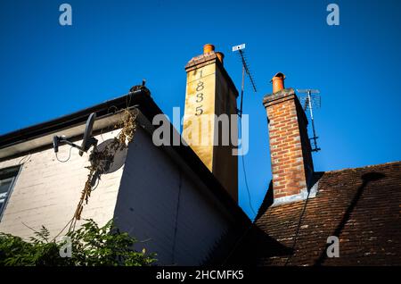 Chimneys with TV aerials on old houses in Billingshurst, West Sussex, UK. One chmney is marked with the number 1835 to show the year it was built. Stock Photo