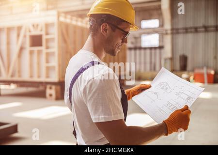 Joyful male worker studying architectural plan at construction site Stock Photo