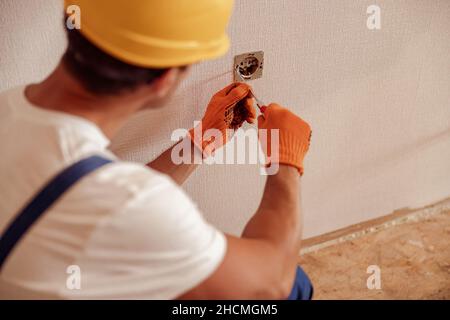 Male electrician hands fixing electrical wall socket Stock Photo