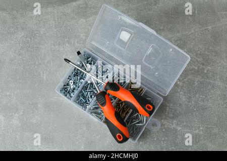 Box with screws and screwdrivers on gray textured background Stock Photo
