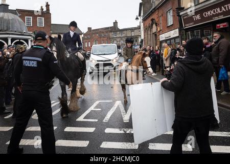 Bungay, Suffolk, UK. 27th December 2021. Pictured: Animal rights activists attempt to block members of the hunt riding through the streets of Bungay. Stock Photo