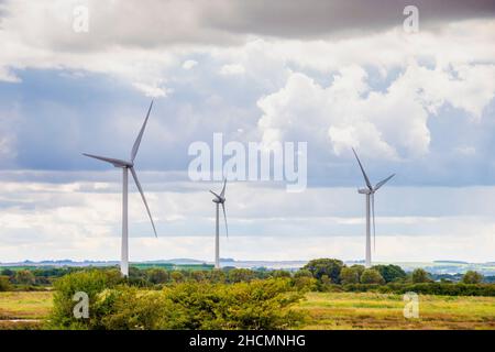 Three wind turbines slowly turn in the air on a cloudy day, Lincolnshire, UK Stock Photo