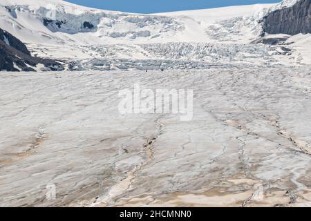 Tourists appear tiny on the massive the Columbia Icefield and Athabasca Glacier at the southern edge of Jasper National Park in Alberta, Canada. The Columbia Icefield is the largest ice field in the Rocky Mountains. Stock Photo