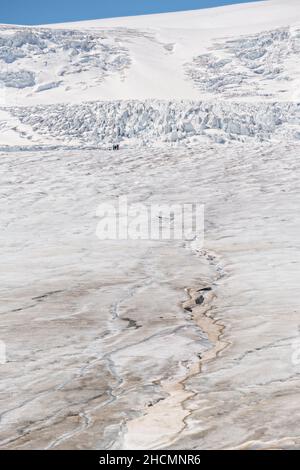 Tourists appear tiny on the massive the Columbia Icefield and Athabasca Glacier at the southern edge of Jasper National Park in Alberta, Canada. The Columbia Icefield is the largest ice field in the Rocky Mountains. Stock Photo