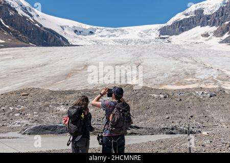 Tourists take photos at the terminal moraine of the massive the Columbia Icefield and Athabasca Glacier at the southern edge of Jasper National Park in Alberta, Canada. The Columbia Icefield is the largest ice field in the Rocky Mountains. Stock Photo
