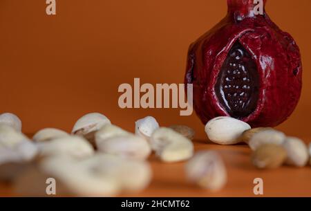 Bottle of wine with the shape of pomegranates on beautiful orange background with Cashew nuts, pistachios and almond Stock Photo
