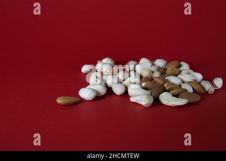 Cashew nuts, pistachios and almonds, scattered on a red background Stock Photo